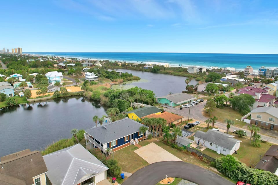 Aerial view of a coastal neighborhood with waterfront homes along a peaceful lagoon, just minutes from pristine beaches and turquoise waters.