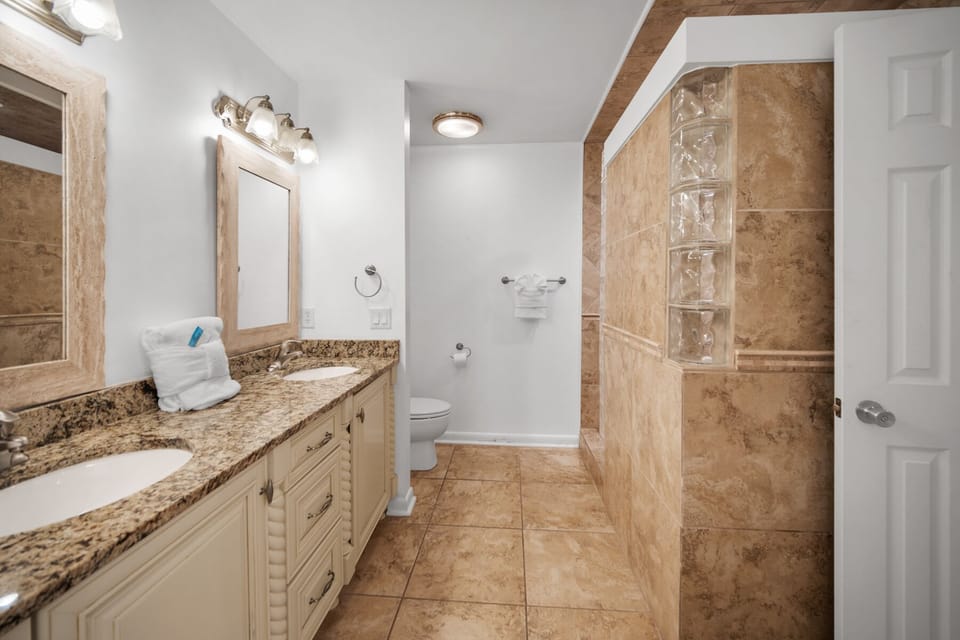 Luxurious marble bathroom with granite counters and glass block shower creates your perfect morning retreat.