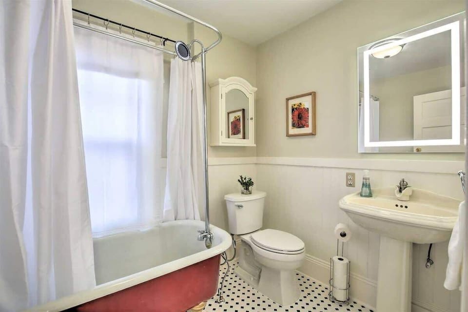 Bright upstairs hall bathroom featuring a classic clawfoot tub, pedestal sink, and charming vintage details.