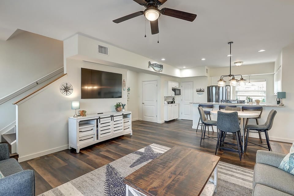 Relax in your spacious open-concept living area with modern furnishings, ceiling fan, and seamless flow to the fully-equipped kitchen.