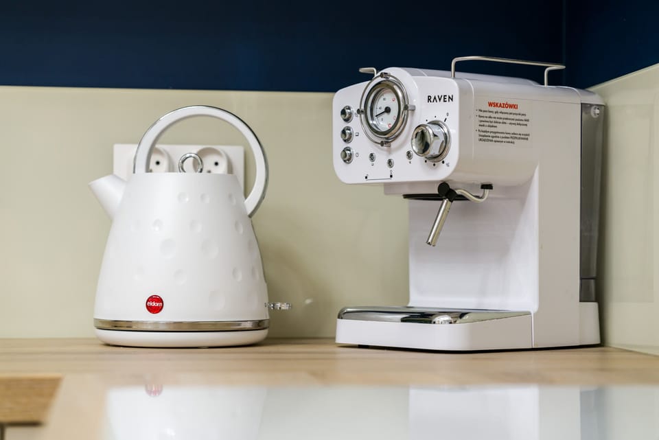 A modern coffee maker and sleek white kettle are neatly arranged on the counter, ready for use.
