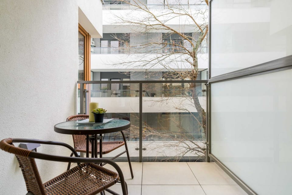 A private balcony with a small table and chairs offers a relaxing spot with a view of the greenery.