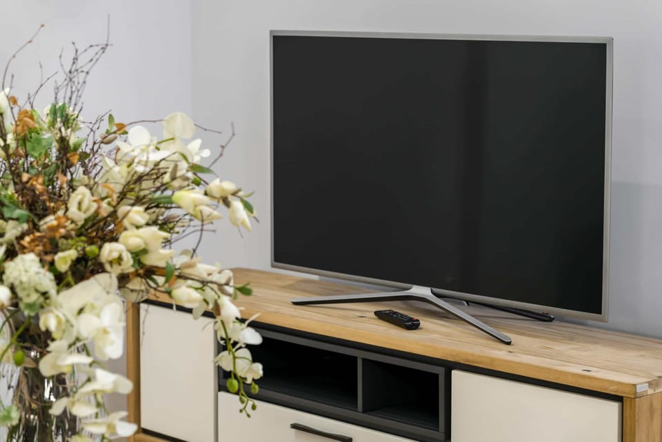 A sleek flat-screen TV sits on a stylish wooden stand, adding entertainment to the living space.

