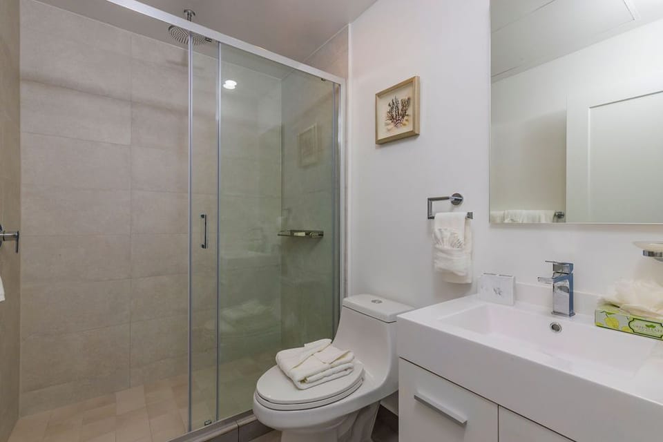 Freshen up in your modern, spa-inspired bathroom featuring a spacious glass shower, sleek fixtures, and plush towels ready for your comfort.