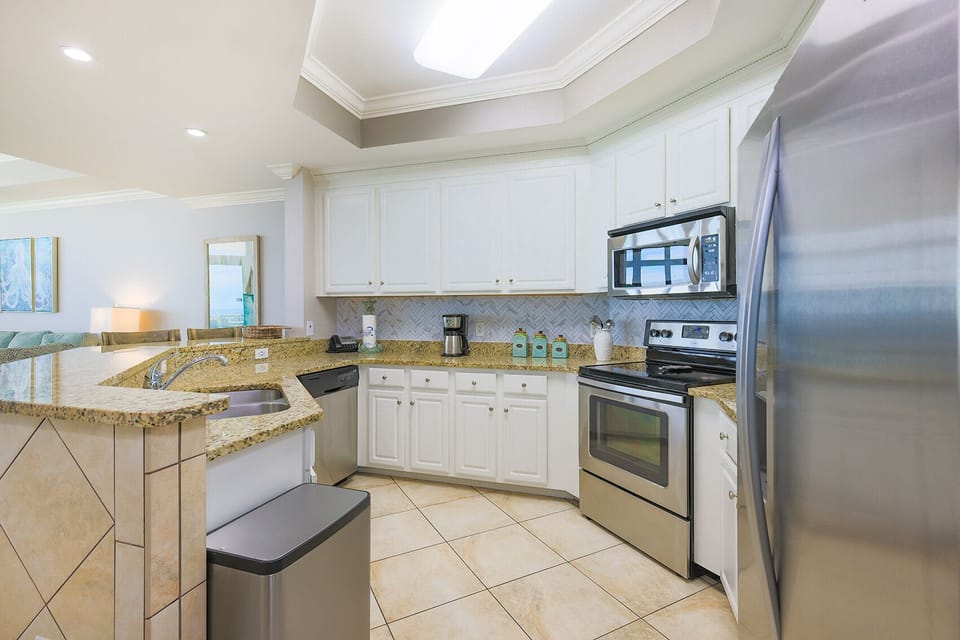 This kitchen features granite countertops, stainless appliances, and a coffee maker, perfect for preparing meals with a view