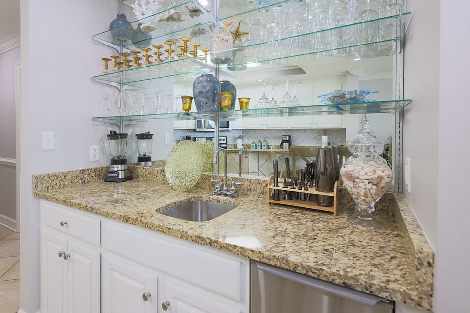 The wet bar features granite countertops, a sleek stainless sink, and well-stocked additions for your cocktail creations