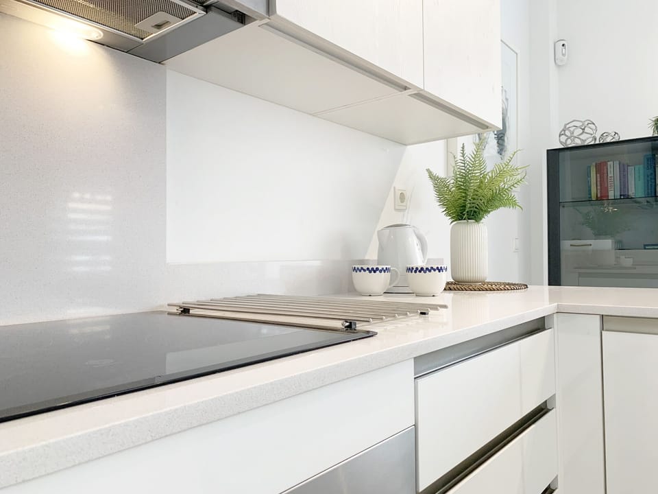 Well-lit kitchen, equipped with stove, refrigerator and storage