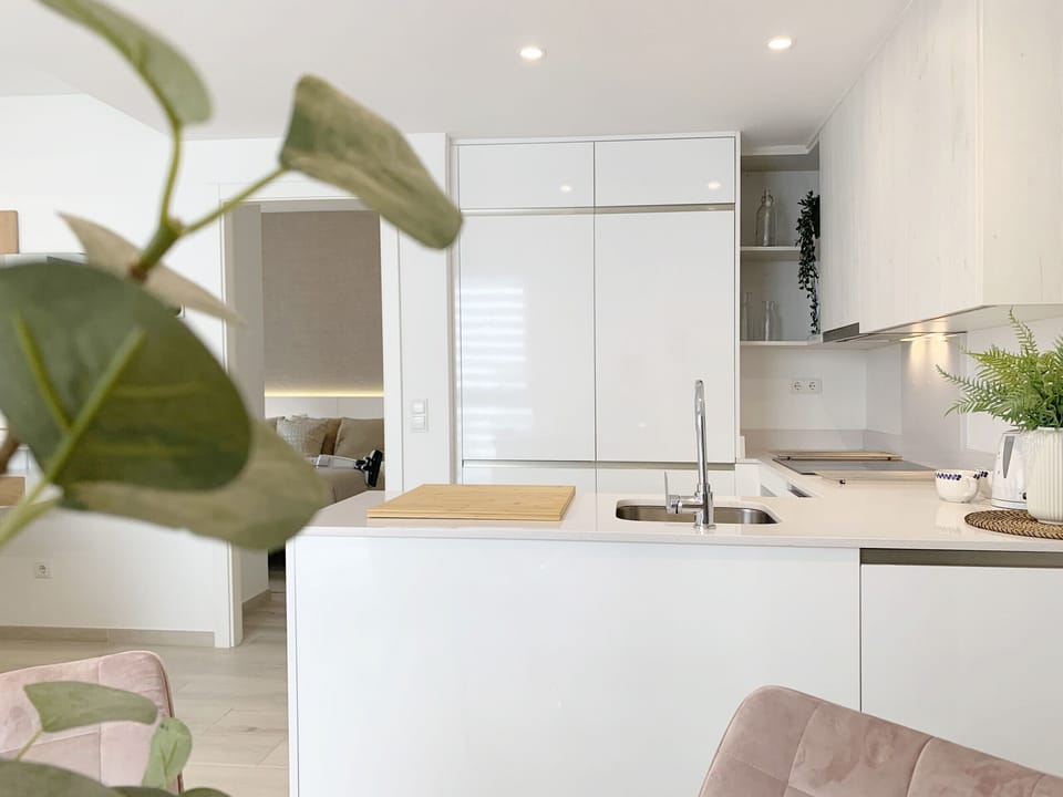 Well-lit kitchen, equipped with stove, refrigerator and storage