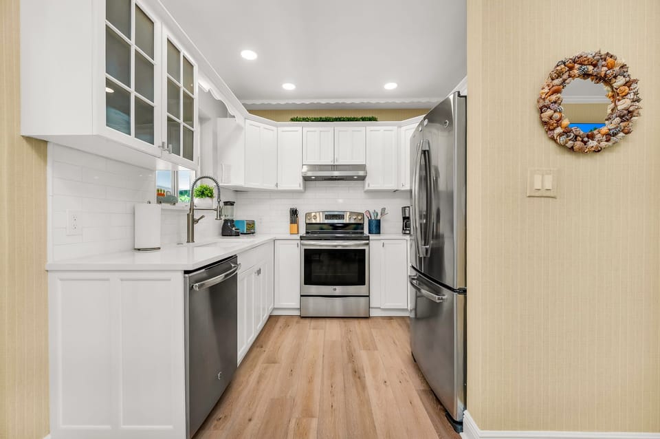 The luminous, fully-equipped kitchen serves as a culinary haven, perfect for post-beach gatherings or sunset cookouts. It's thoughtfully stocked with all the essentials for cooking, whether you're dining indoors or outdoors.