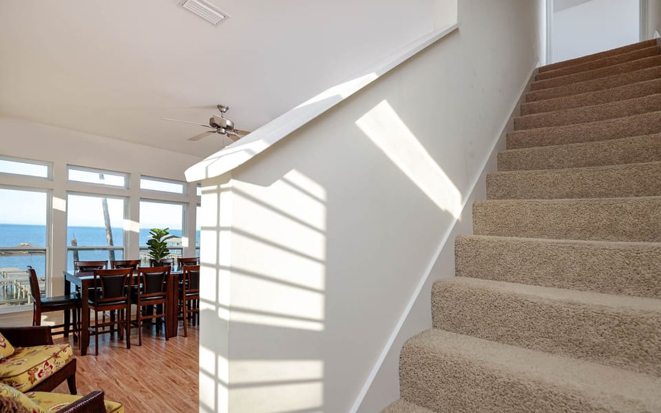 The living area features a dining table with a bay view, complemented by natural light streaming through large windows