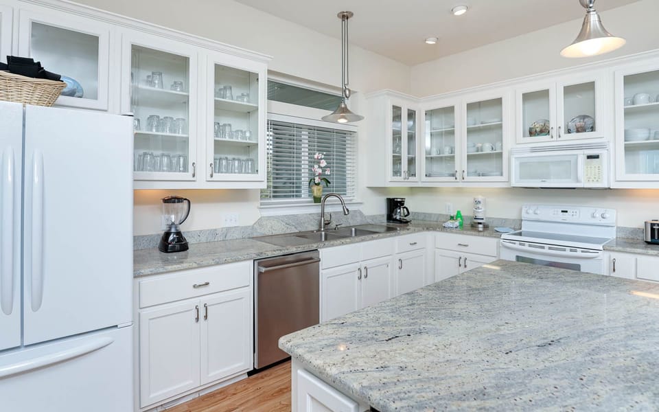 The modern kitchen features a stainless dishwasher, granite countertops, and a view of the bay, perfect for culinary adventures