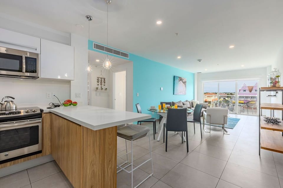 Gather around this open, sun-filled space where the kitchen flows into your dining area. Sleek counters, modern appliances, and pops of color invite you to cook, dine, and unwind with ease.