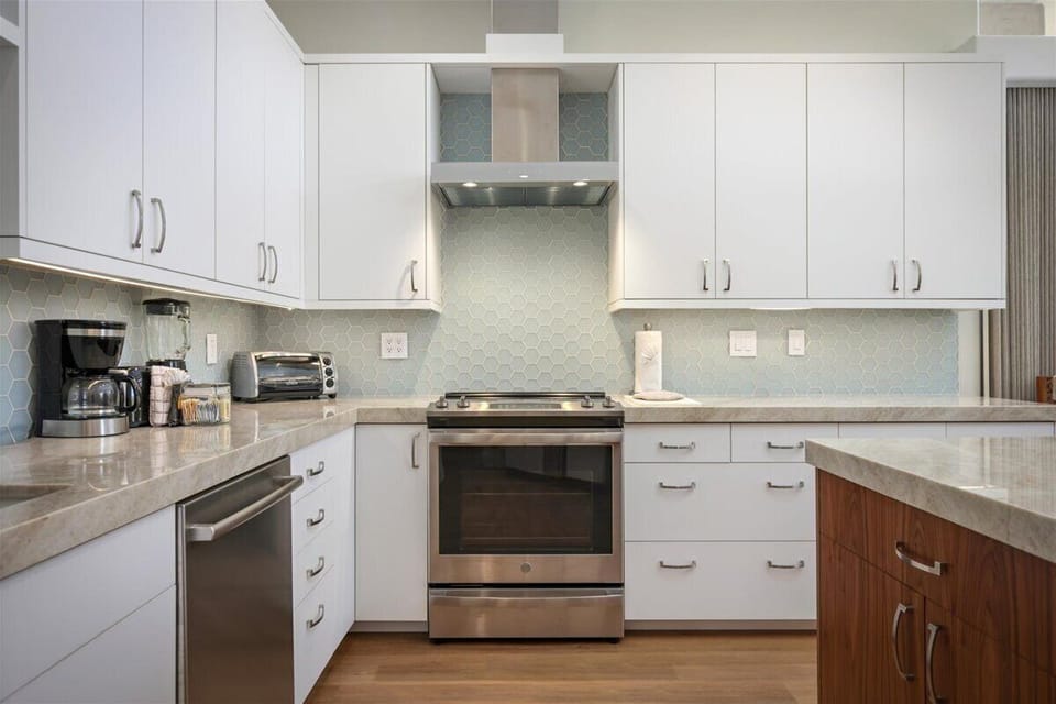 Your modern kitchen awaits with sleek white cabinetry, elegant hexagonal tile backsplash, and polished countertops. Stainless steel appliances and ample prep space make cooking a pleasure in this bright, contemporary space.