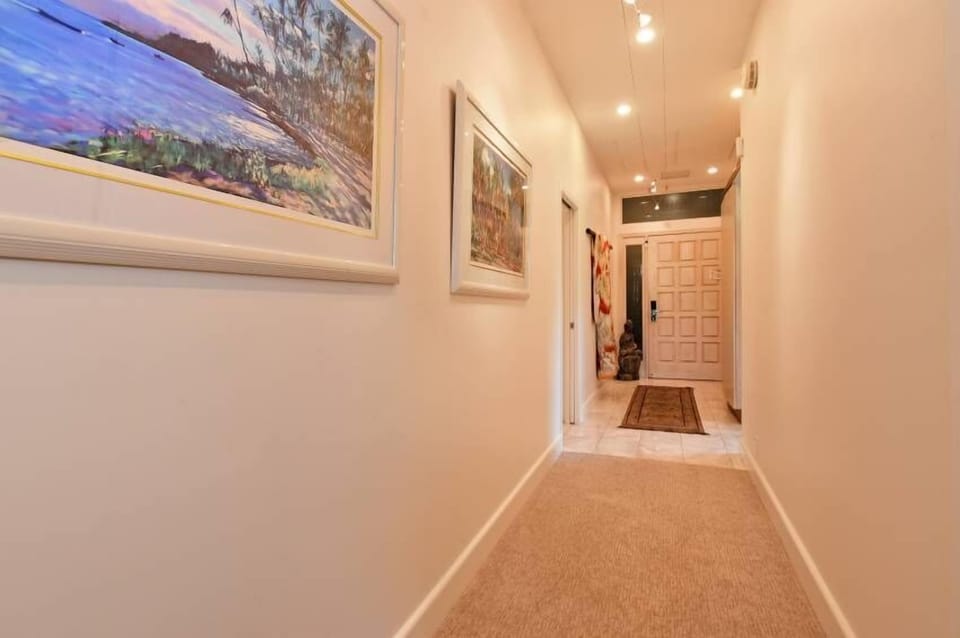 A welcoming hallway adorned with coastal artwork leads to the entrance, setting a relaxed, beachy tone from the moment you arrive at this comfortable retreat.