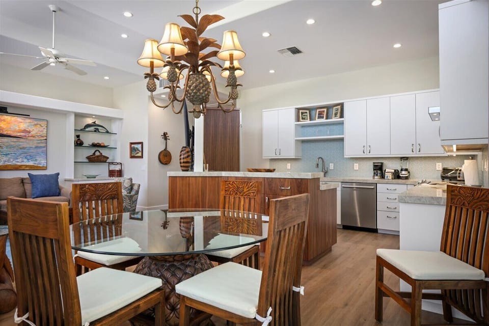Picture yourself cooking in this beautifully appointed kitchen, where warm wood tones meet modern convenience. Gather around the glass dining table under a charming pineapple chandelier, sharing meals and making memories.