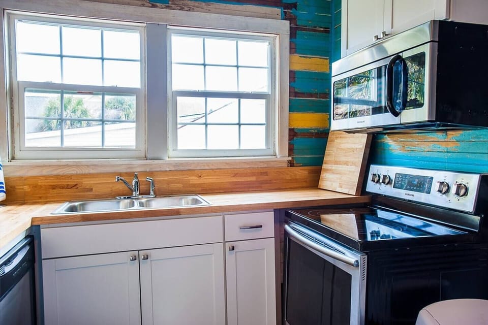 Kitchen with the original old wood painted wall that makes a statement in these boho beachy colors of turquoise, marigold and eggshell