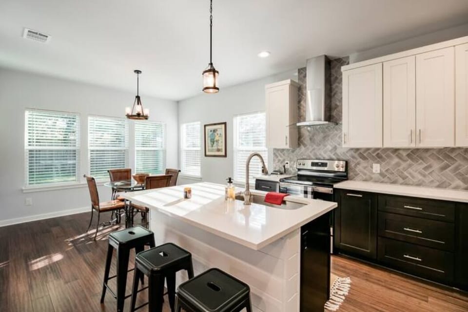 Kitchen has a table w/ 4 chairs and 3 barstools
