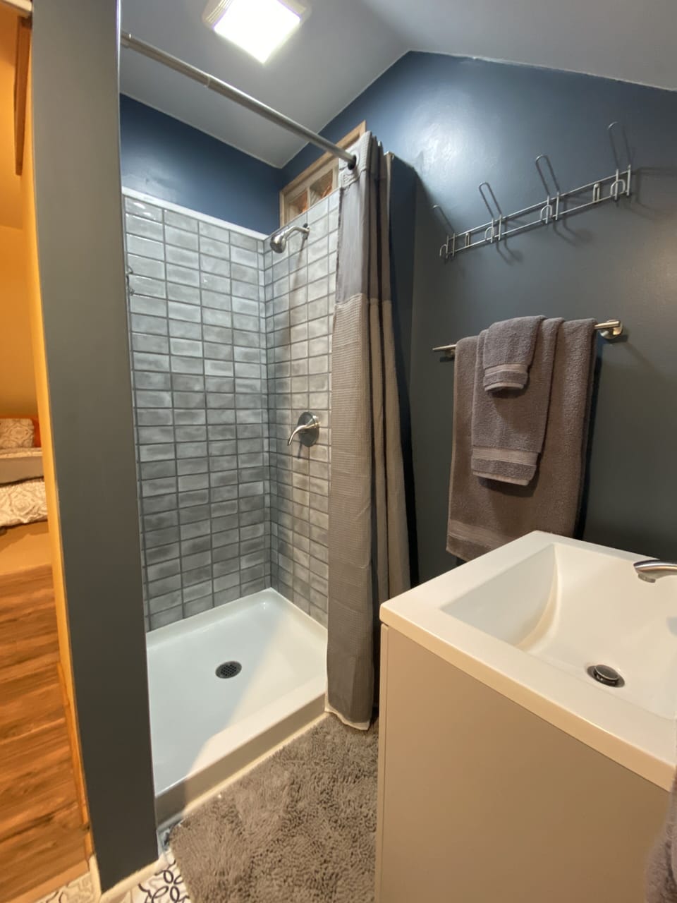 Bathroom has lovely tiled shower stall and small storage closet with shelves.