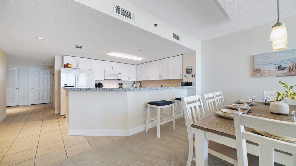 Dine in style with ample space for everyone. This inviting dining area features a charming table for family meals, complemented by additional seating at the convenient breakfast bar.