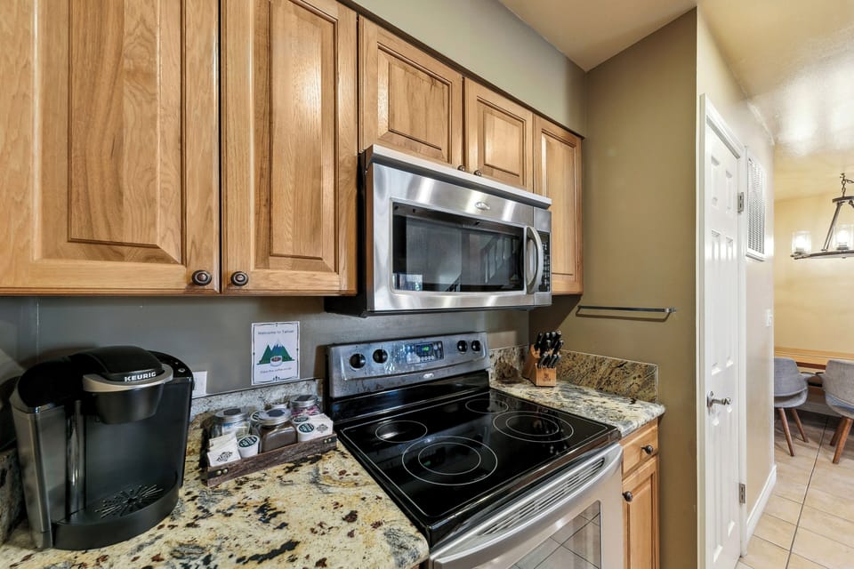 Your fully equipped kitchen features granite counters, stainless appliances, and warm wood cabinets—perfect for preparing home-cooked meals during your stay.