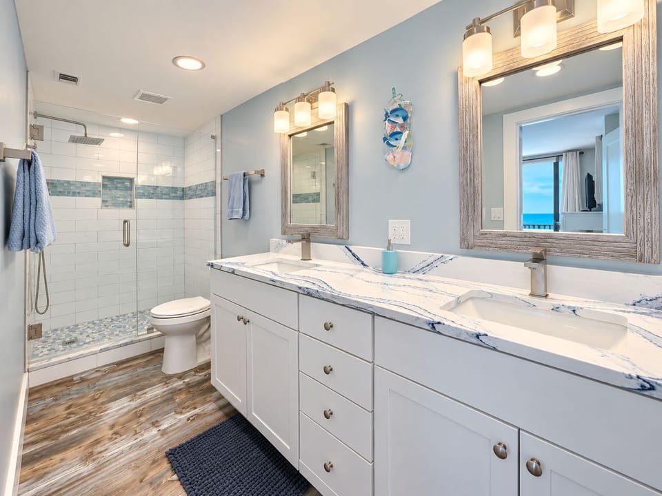 Large bathroom with double vanities and a modern walk in shower.