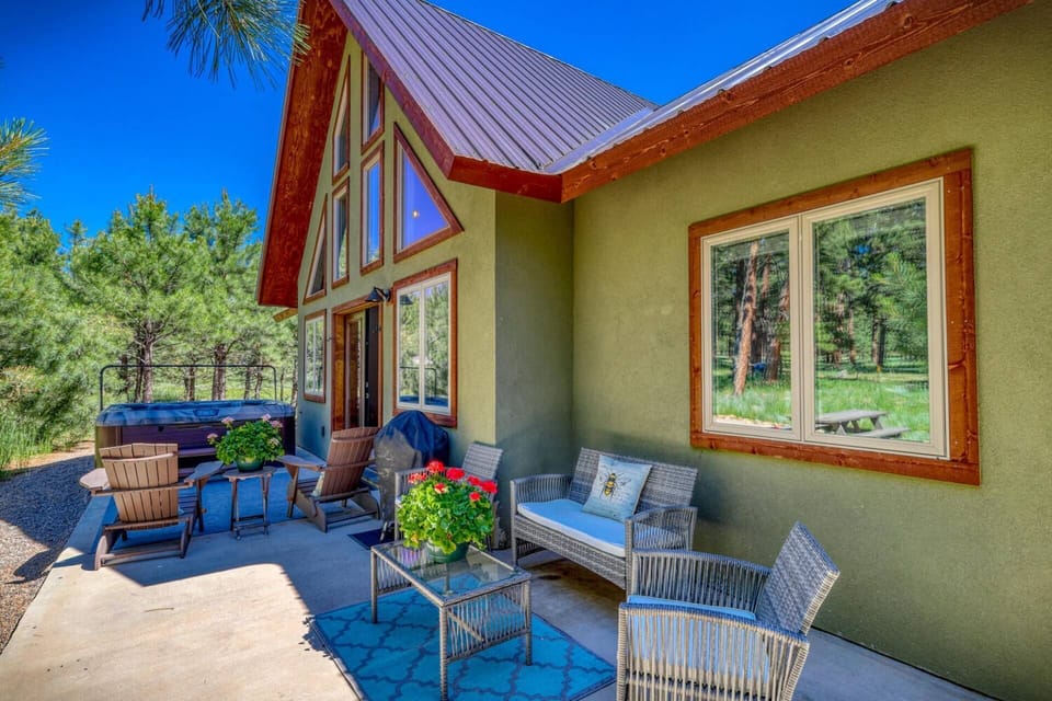 The back patio is a slice of heaven with a bubbling hot tub, grill, outdoor seating, and swaying pine trees.