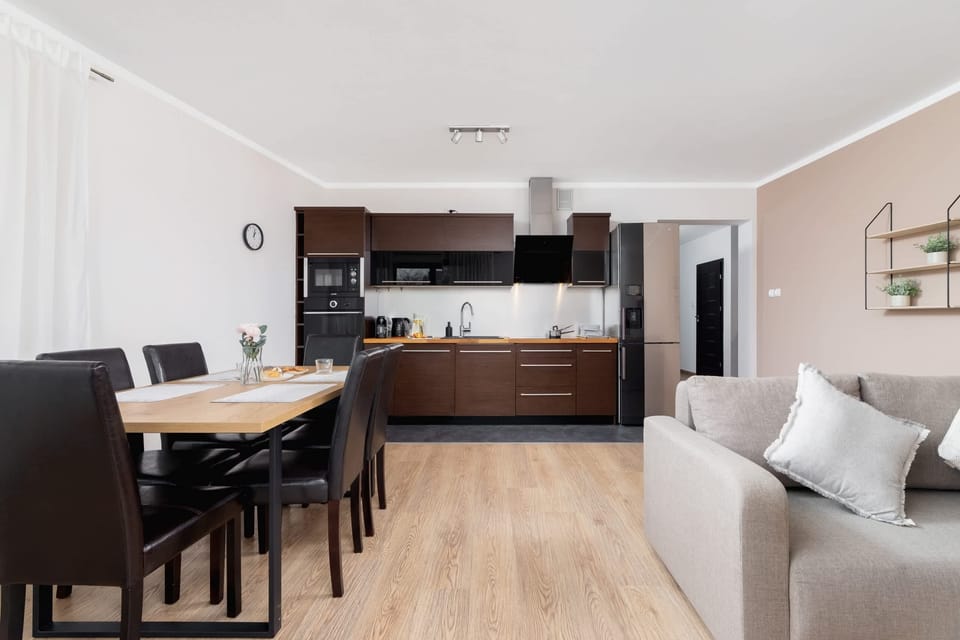 Another angle of the living and dining space, featuring a comfortable sofa and a wooden dining table for six.