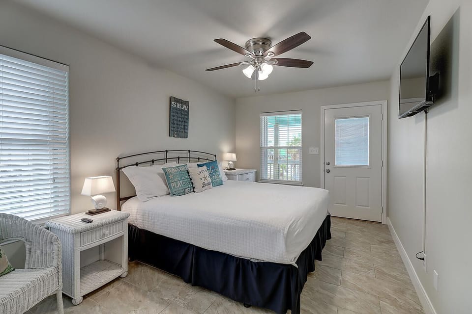 Unwind in your bright coastal bedroom with a comfy bed, ceiling fan, and TV for perfect relaxation.
