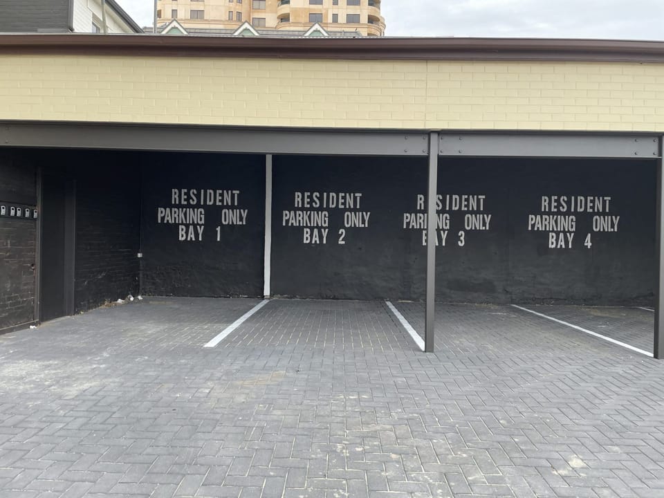 All parking is unnumbered and allocated on a first-come, first-served basis, including extra bays opposite the carport and beneath the outdoor staircase.