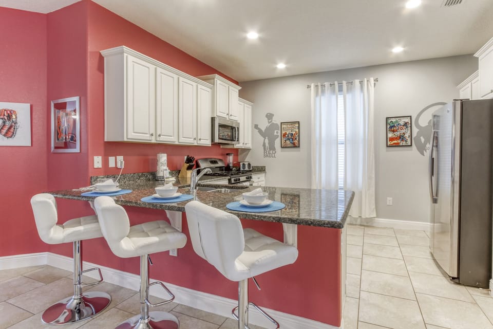 The fully equipped kitchen features a peninsula with three bar stools.