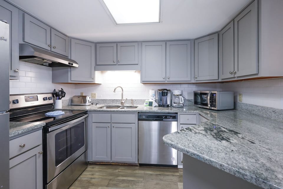 The kitchen features gray cabinetry, granite countertops, Keurig and coffee maker, creating a functional cooking space