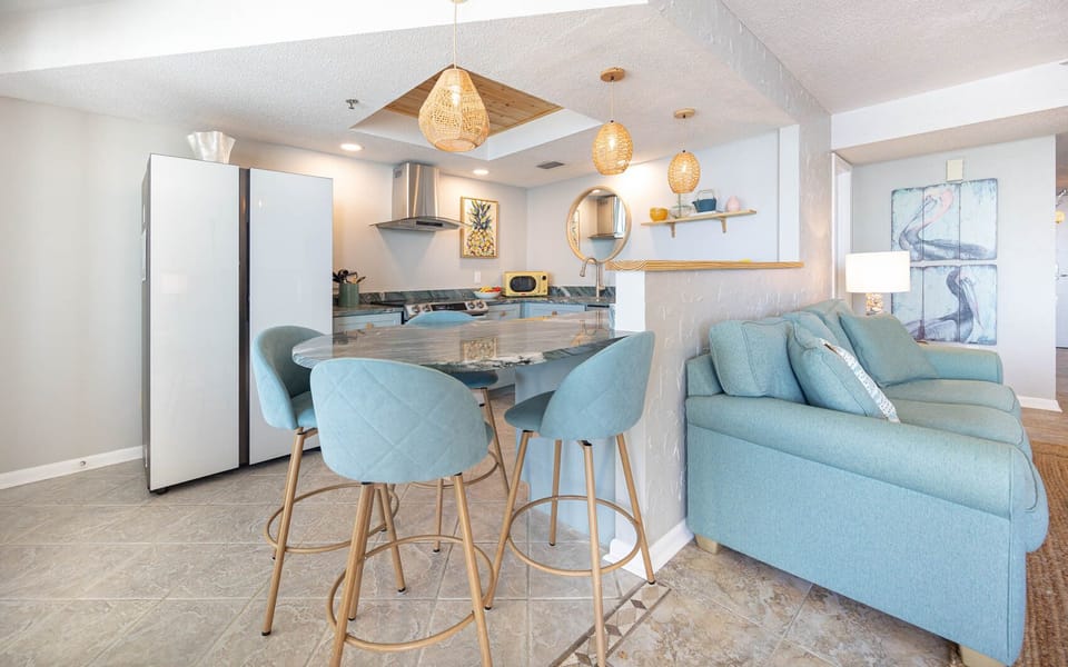 This kitchen features modern smart appliances, a stylish countertops, and a cozy dining area with chic bar stools
