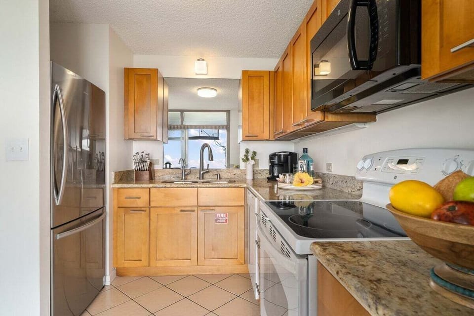 A bright kitchen featuring granite countertops, stainless steel appliances, and ample storage space