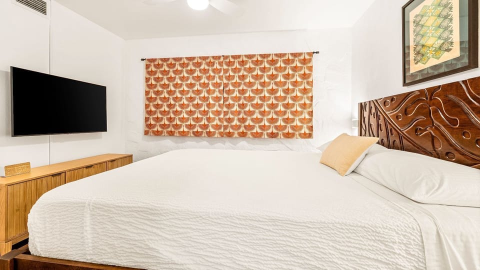 Bedroom features a California king bed, soft lighting, and large TV