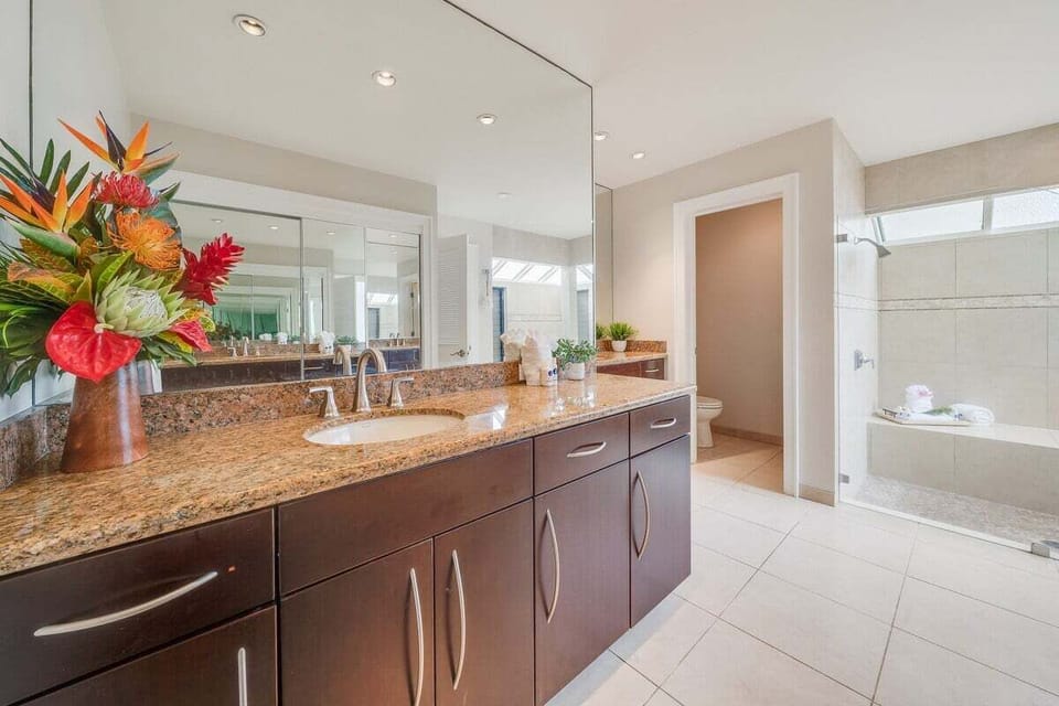 Updated bathroom with a spacious vanity, granite countertop, and bright lighting, designed for comfort and convenience during your stay.