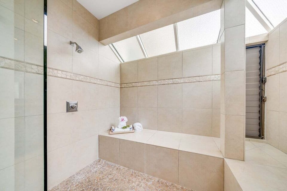 Modern walk-in shower with tiled surround and high windows that allow in natural light while maintaining privacy.