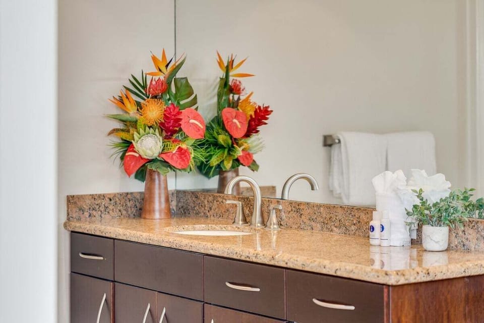 Updated bathroom featuring a granite vanity, modern fixtures, and fresh floral touches that create a bright and welcoming space.