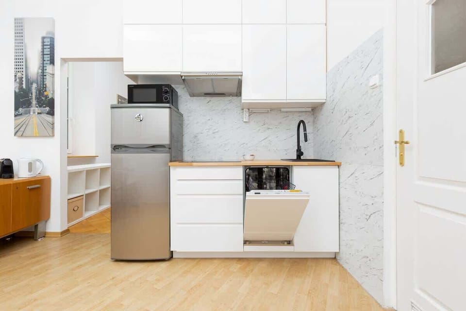 A fully equipped kitchen with white cabinetry, a refrigerator, and a sleek countertop.
