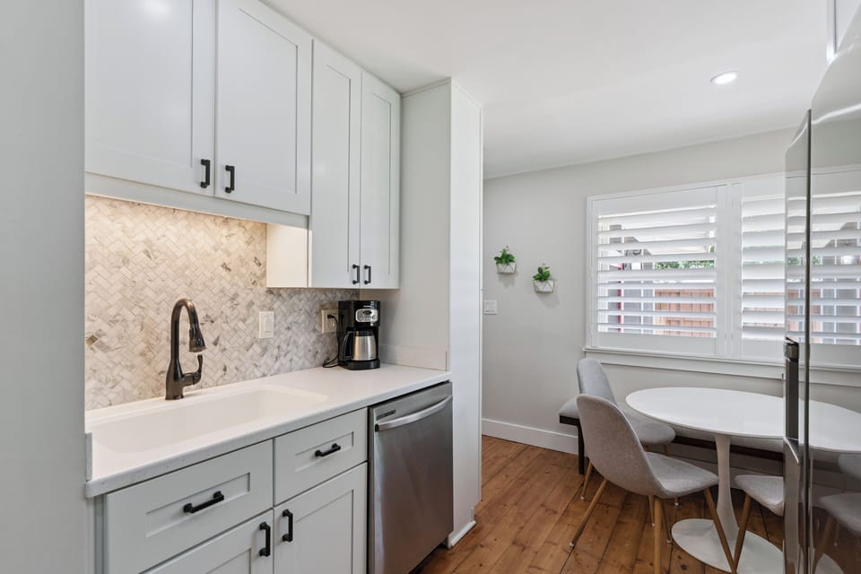 Step into your bright, modern kitchenette with elegant herringbone backsplash, white counters, and a cozy breakfast nook by the window—perfect for morning coffee.