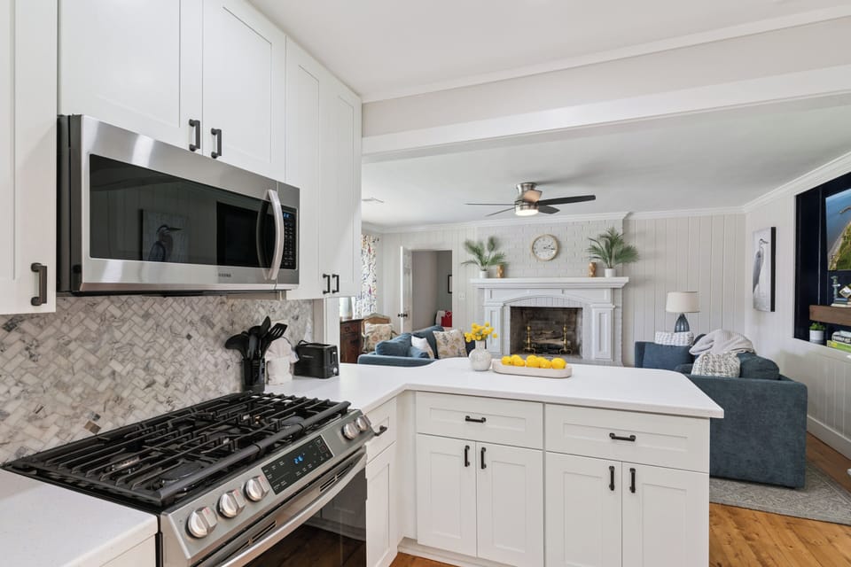 Your open-concept kitchen flows into a cozy living room complete with a fireplace, blending modern convenience with coastal charm for relaxing evenings in.