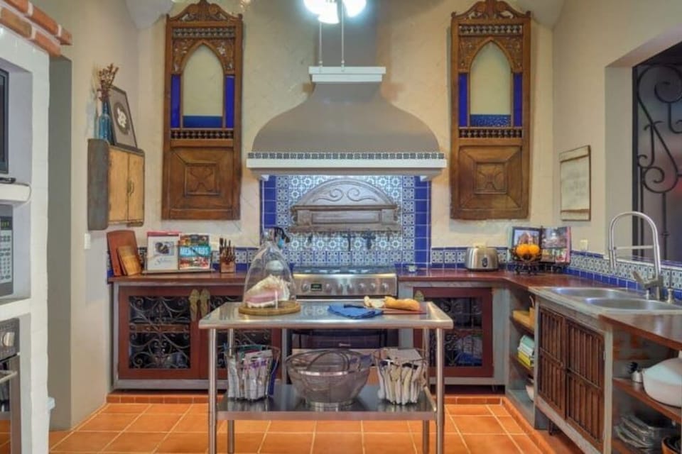 The chef's kitchen, view of ovens, stove, dishwasher, microwave, TV, and island.