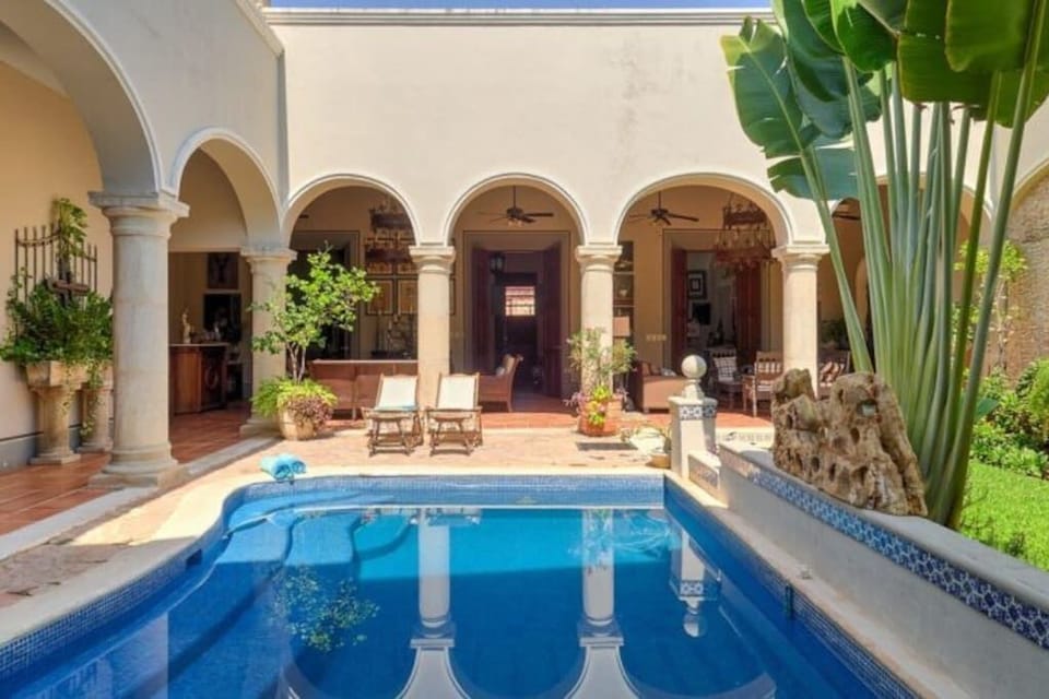 Pool area in the day, facing the front of the property and outdoor living rooms.