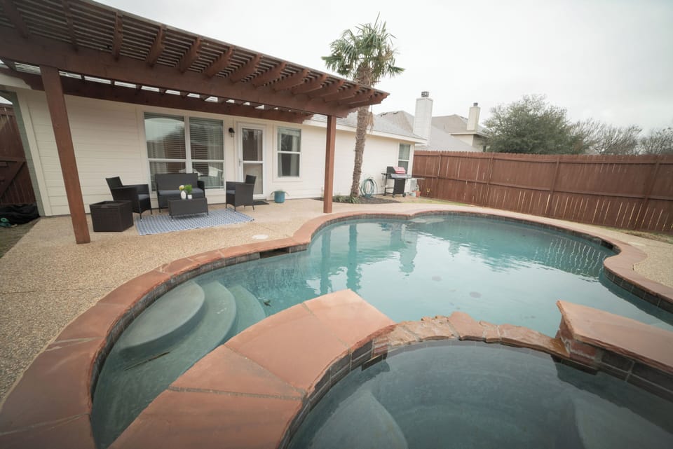Pool + hot tub with pergola and patio sitting plus a grill and outdoor fire pit.