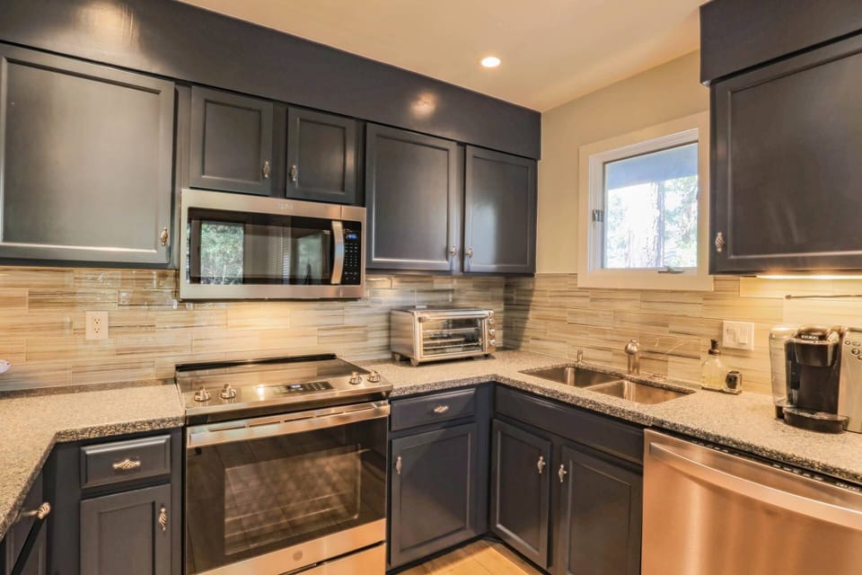 The kitchen features stainless steel appliances, a tiled backsplash and blue cabinets.