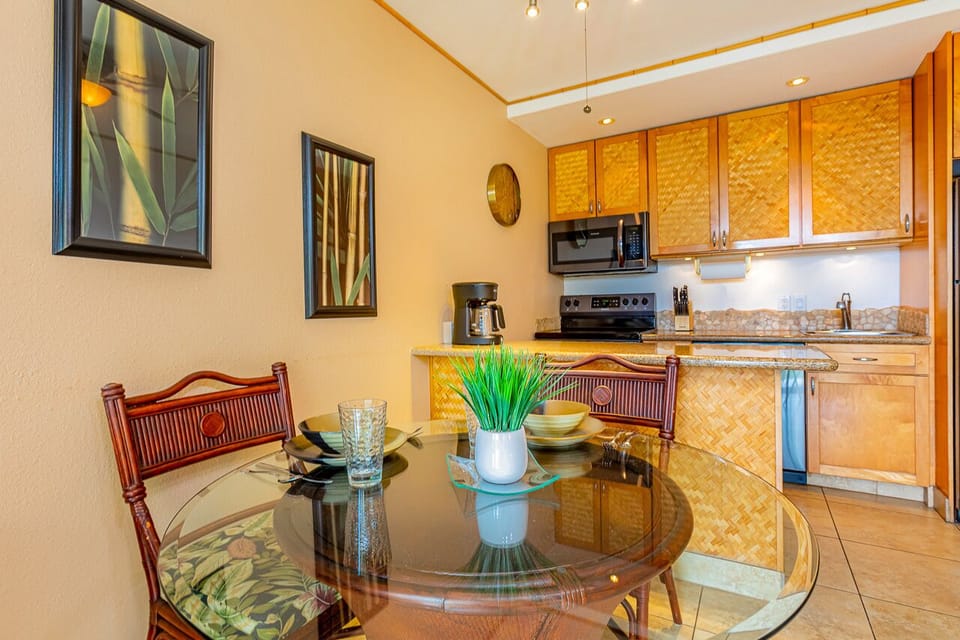 Step into your tropical-inspired kitchen and dining area, featuring warm bamboo cabinetry and a welcoming table set for your morning coffee.