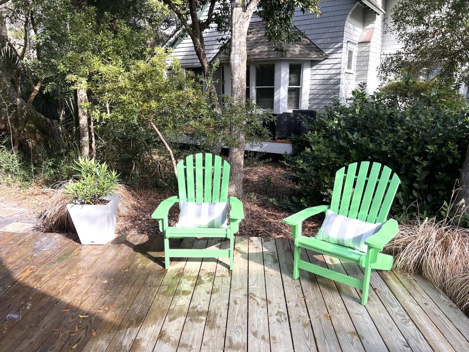 Large front deck with Adirondack chairs and potted Oleander.
