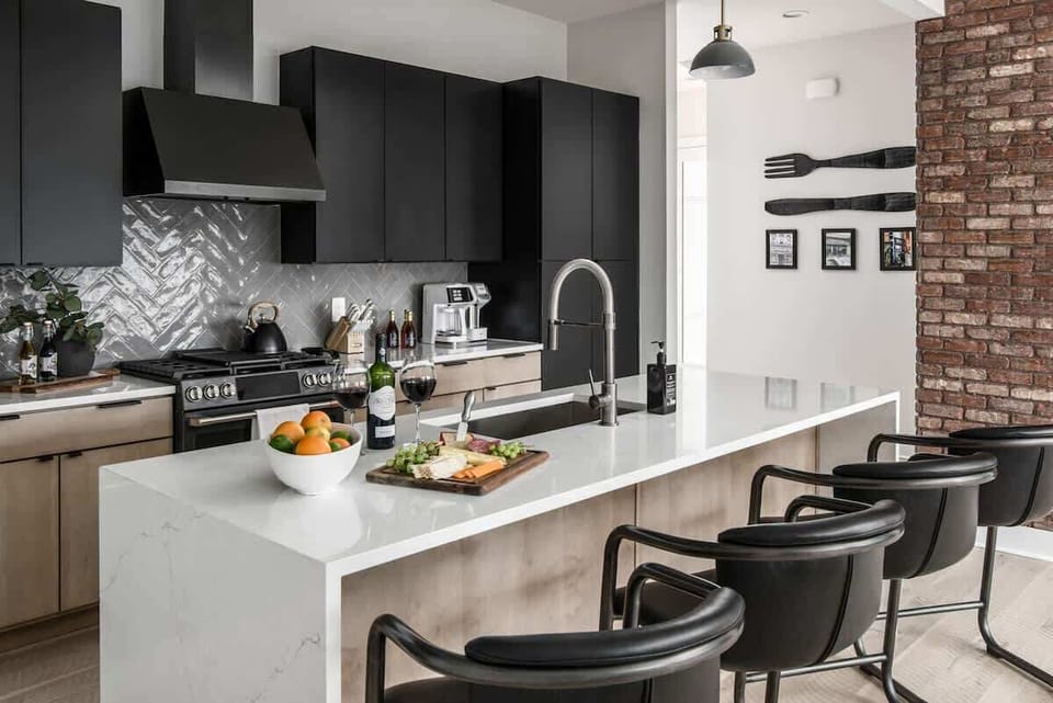 Sleek and modern kitchen with all black cabinetry and appliances. Island with bar seating.