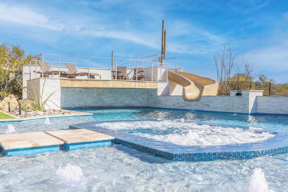 The oversized pool features multiple depths, a thrilling water slide, and built-in infinity spa