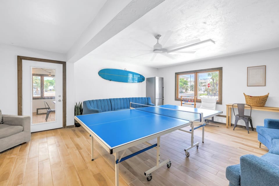 Play and relax in the spacious game room featuring a full-size ping pong table, plenty of seating, and natural light.