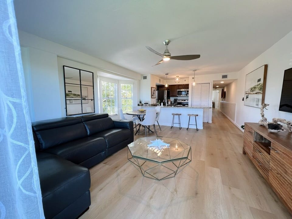 View from balcony into living area showing sofa (w/ a recliner seat) & kitchen